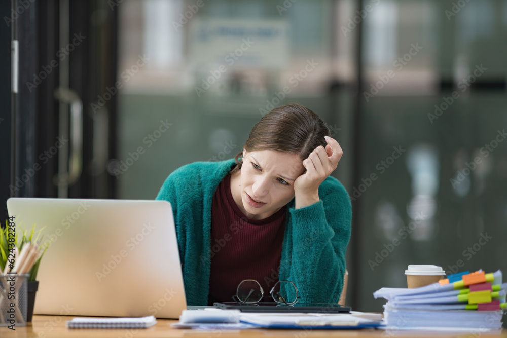 A tired businesswoman under stress works at a laptop while sitting at a table at home and holds her hand on her temples, migraine attacks. A tired businesswoman under stress works at a laptop while sitting at a table at home and holds her hand on her temples, migraine attacks.