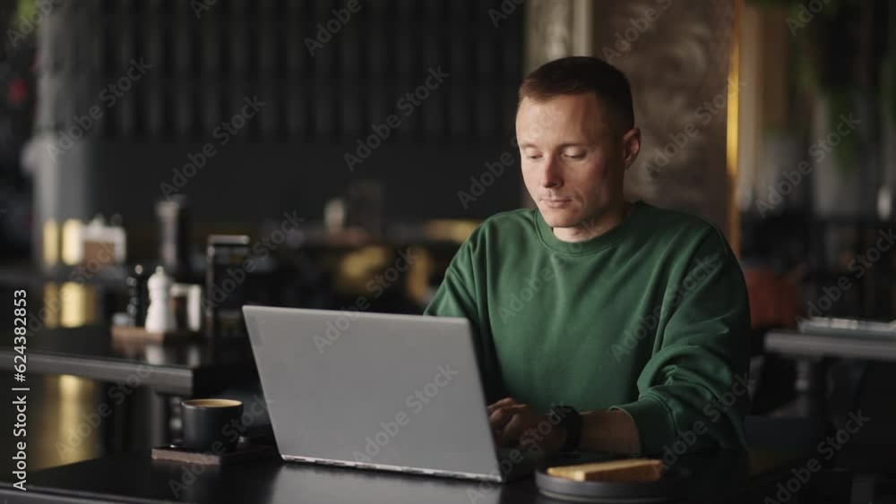 Man In Green Sweater Working With Laptop In Cafe, Smart Guy Is Programmer Or Web Developer Man In Green Sweater Working With Laptop In Cafe, Smart Guy Is Programmer Or Web Developer
