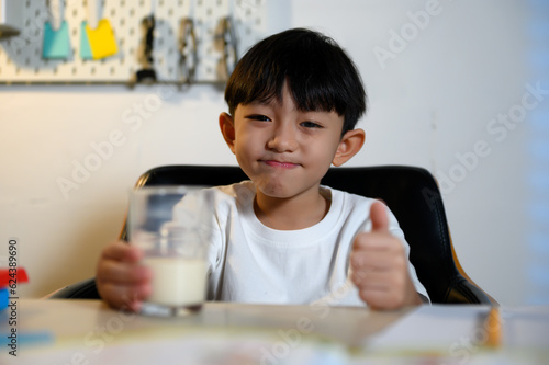 Asian Children's Student Drinking Milk Break After Learning for Refreshment at Home, Early Education, Studying, and Healthy Habits at Home.
