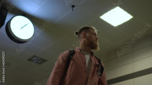 the guy is standing in the lobby of the subway. bottom view