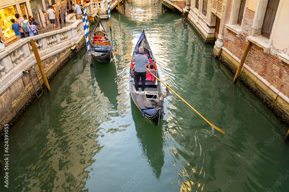 Gondola ride in Venice (Venedik, Venetian). Traveling in a traditional gondola through narrow ancient canals. Italy