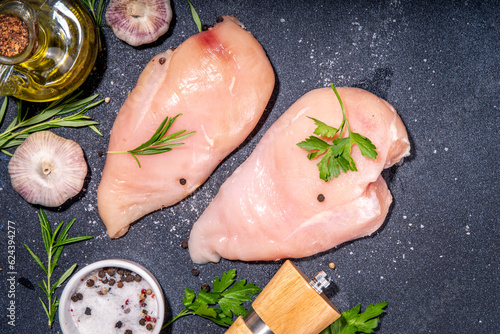 Raw chicken breast, white meat fillet steaks with greens, olive oil, spices, dinner cooking background top view copy space