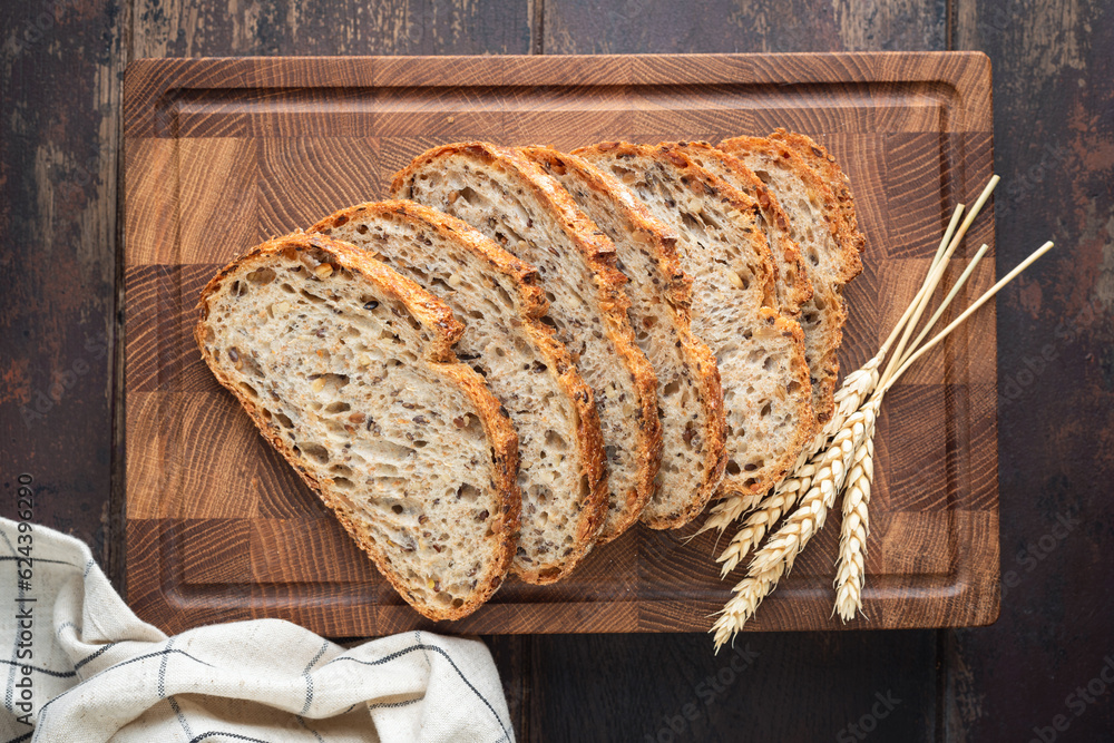 Whole wheat artisan sourdough bread sliced on a wooden cutting board, top view. Healthy bread - obrazy, fototapety, plakaty 