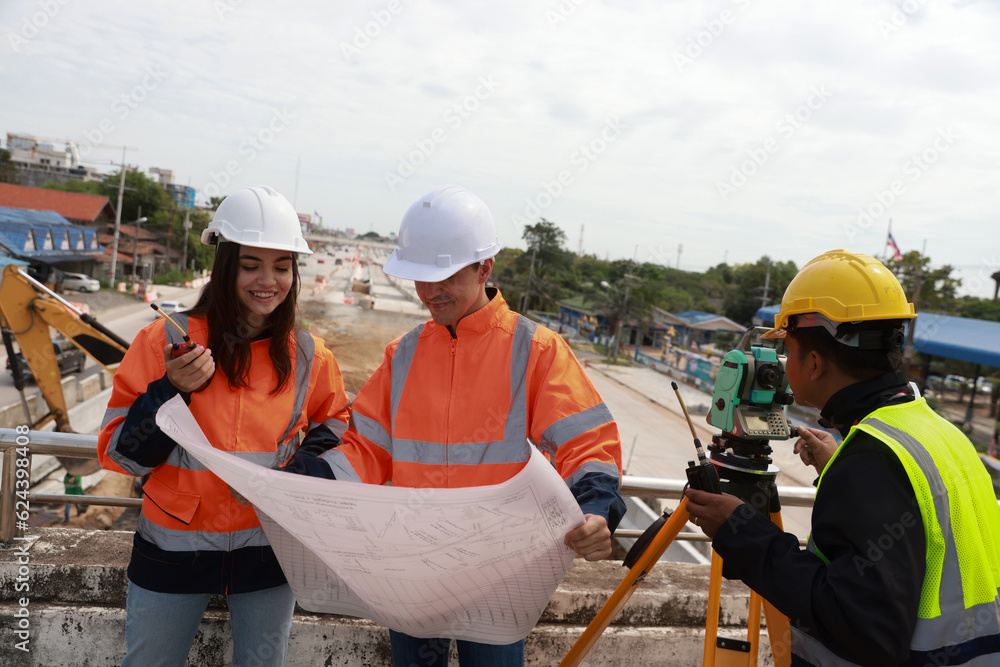 A civil team of engineers works with a blueprint at the Construction Site of New Concrete Roads and Bridges forming a Major Urban Infrastructure. A civil team of engineers works with a blueprint at the Construction Site of New Concrete Roads and Bridges forming a Major Urban Infrastructure.