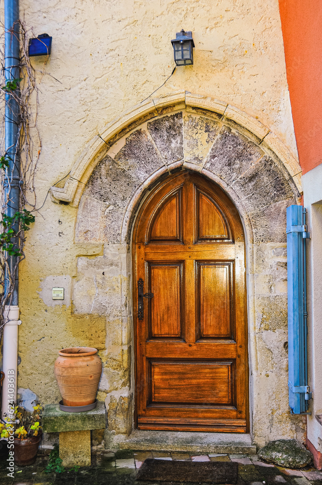 Front view of, a wood front door with limestone, arched, decorative entry way of a 1500's building