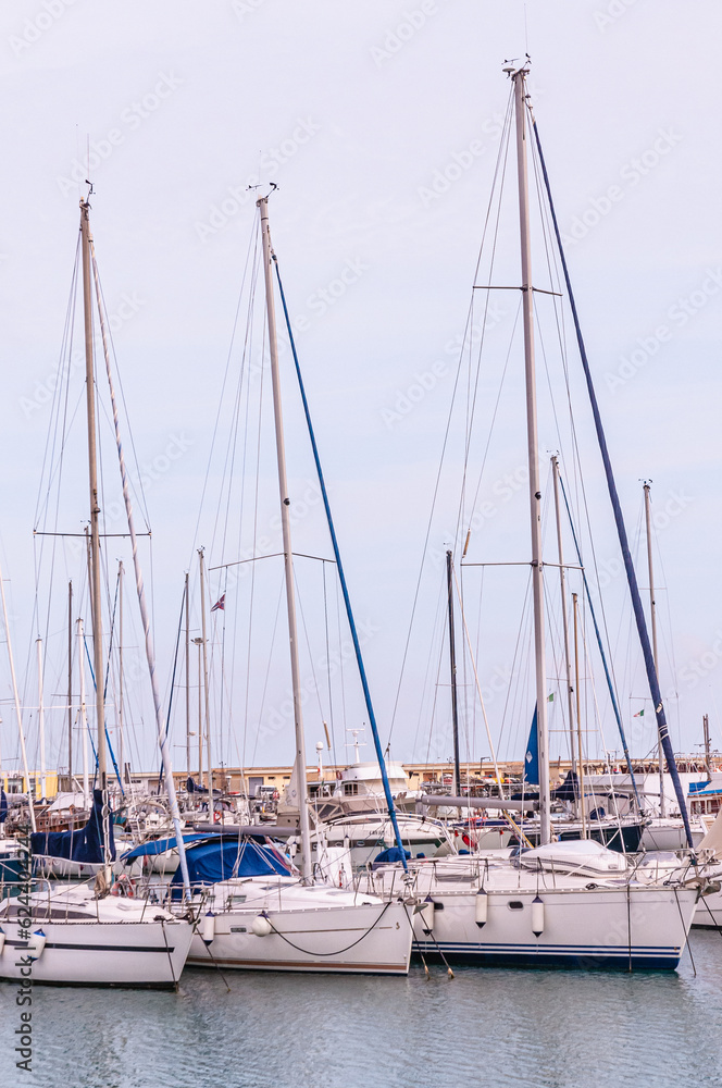 Front view, medium distance of, a  row of tall, sailing ships, at an Italian harbor, on Adriatic coastline
