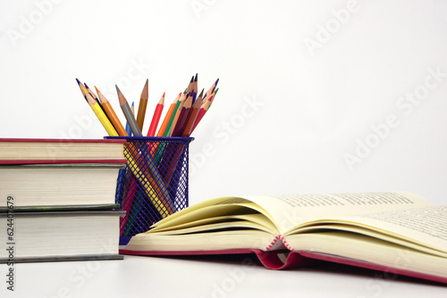 Crayon or colored pencils in box and the book placed in the blurred background. Knowledge and education concept.