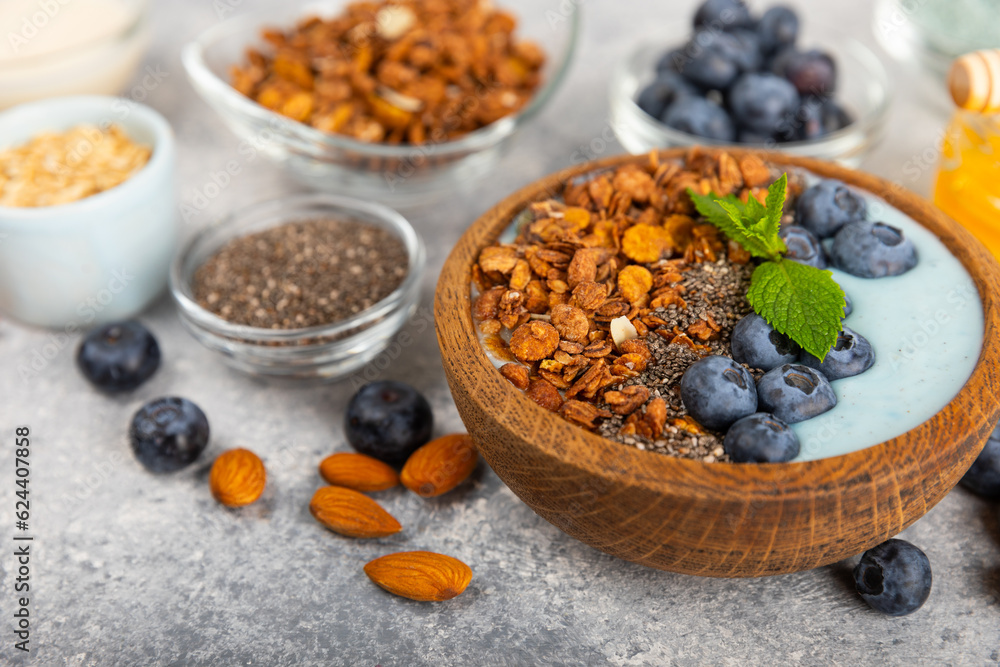 Granola bowl with yogurt and fresh almonds, blueberries, raspberries,peach and strawberries on a marble kitchen table.Acai and spirulina bowl.Healthy breakfast concept.copy space.Place for text. Granola bowl with yogurt and fresh almonds, blueberries, raspberries,peach and strawberries on a marble kitchen table.Acai and spirulina bowl.Healthy breakfast concept.copy space.Place for text.