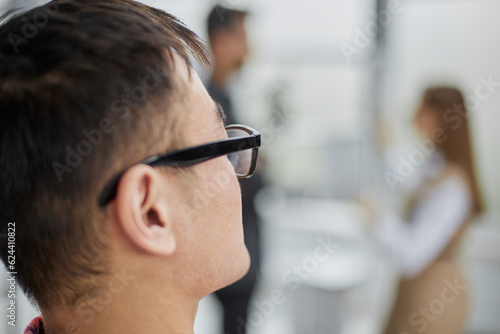 Headshot, portrait of millennial male employee looking away in coworking office