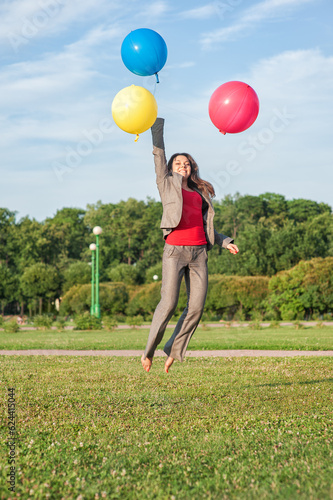 Young beautiful happy business woman with long hair jumping with air balloons outdoor