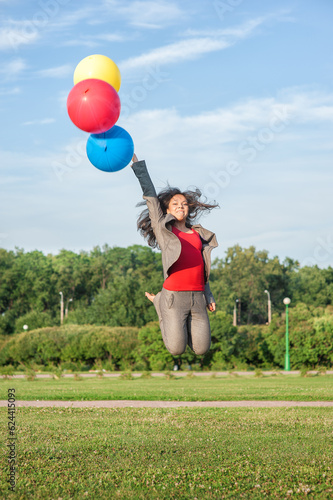 Young beautiful happy business woman with long hair jumping with air balloons outdoor