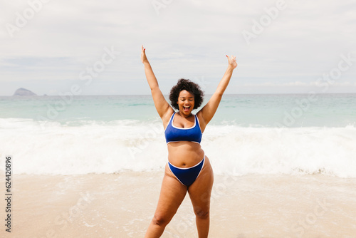 Happy plus size woman in a bikini celebrating and having fun at the beach