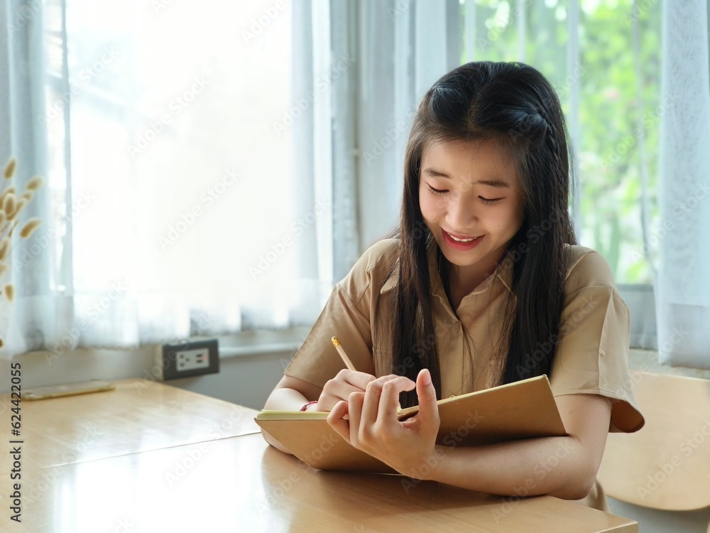 Happy of Young asian teen girl college student Taking written Notes to on notebook.Online education, elearning concept,freelance people businessfemale Happy of Young asian teen girl college student Taking written Notes to on notebook.Online education, elearning concept,freelance people businessfemale