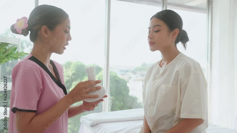 Introducing Thai masseuse massage with herbal compress for young customers at the modern wellness center. Introducing Thai masseuse massage with herbal compress for young customers at the modern wellness center.
