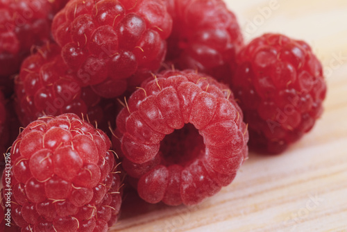 Heap of fresh ripe and sweet raspberries on wooden table. Red raspberries. Macro shot.