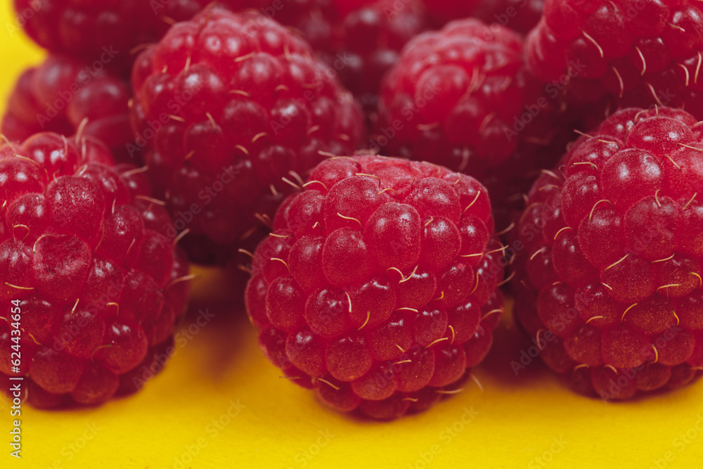 Heap of fresh ripe and sweet raspberries on yellow background. Red raspberries. Macro shot. Heap of fresh ripe and sweet raspberries on yellow background. Red raspberries. Macro shot.