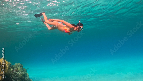 Brunette woman with snorkeling mask and tube swimming in the sea. Underwater view.
