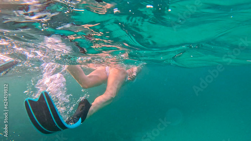 Brunette woman with snorkeling mask and tube swimming in the sea. Underwater view.