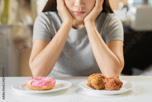 Diet  Dieting hand of woman choosing between sweet donut  snack or fried chicken  junk food  choose eat food for good healthy  health when hungry  Weight loss person  isolated over white background.