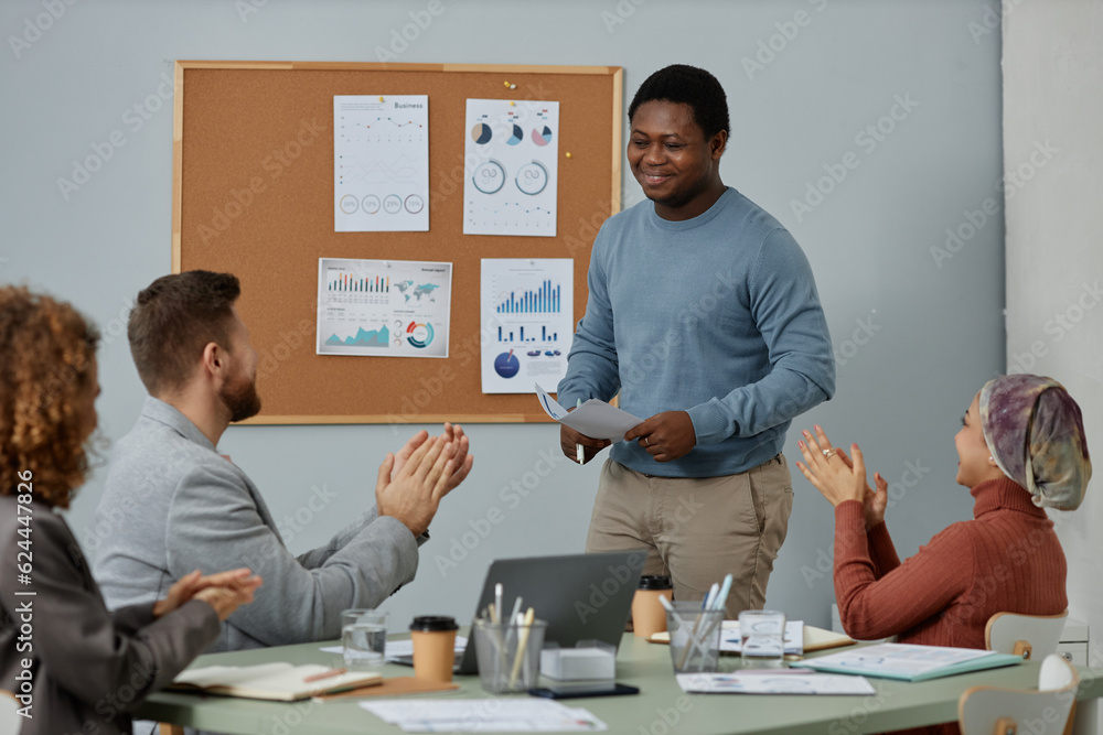 © Seventyfour - Happy young African American businessman standing in front of audience congratulating him on successful speech or presentation by ovations © Seventyfour - Happy young African American businessman standing in front of audience congratulating him on successful speech or presentation by ovations