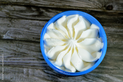 vanilla white frozen ice cream in a plastic bowl isolated on wooden background and ready to be served, a vanilla ice cream in a flower shape in blue container, selective focus