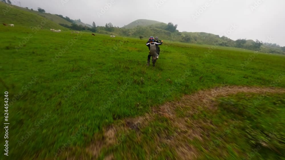 Enduro motorbike biker speed riding extreme stunt tricks wheely on green valley field aerial view. FPV sport drone close shot male racer standing on back wheel motorcycle adrenalin travel adventure 4k Enduro motorbike biker speed riding extreme stunt tricks wheely on green valley field aerial view. FPV sport drone close shot male racer standing on back wheel motorcycle adrenalin travel adventure 4k