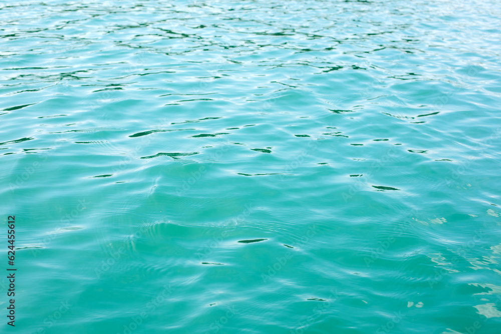 Abstract nature textured background, water waves in the lake with sun reflection, clear blue-green water