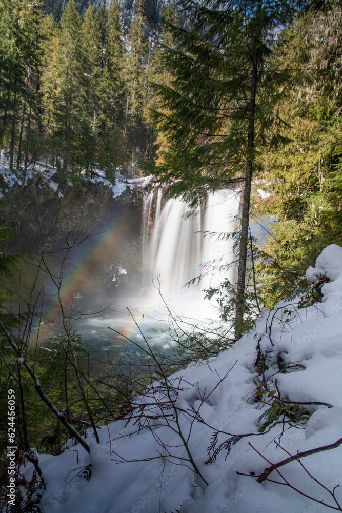 View of a waterfall immersed in a snowy green forest in Oregon, United States. View of a waterfall immersed in a snowy green forest in Oregon, United States.