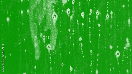 Foam dripping on glass with a greenscreen background with bubbles