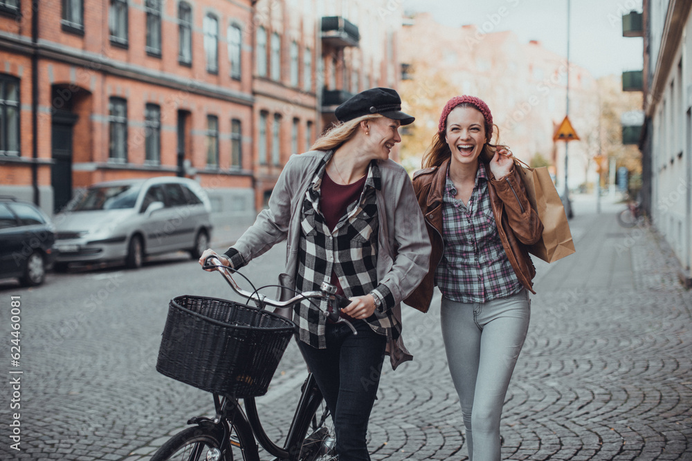 Young women pushing their bicycles on a city street Young women pushing their bicycles on a city street