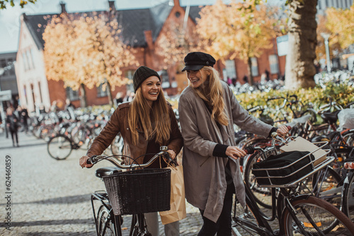 Young women pushing their bicycles on a city street
