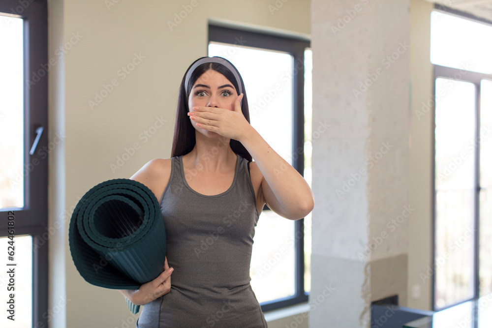 pretty young woman covering mouth with a hand and shocked or surprised expression. yoga concept pretty young woman covering mouth with a hand and shocked or surprised expression. yoga concept