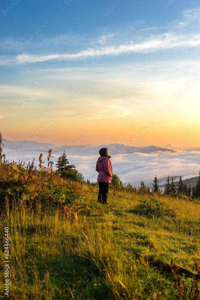 landscape in the mountains, sunset sunrise a girl looks at the horizon of the sun's rays without a face from the back travel conquering the peaks tourist hiking,Montenegrin mountain range Carpathians