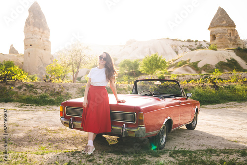 beautiful happy girl in a skirt posing near a retro car in the mountains of cappadocia