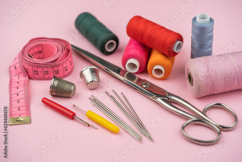 various tailor accessories and tools for tailoring on a pink background