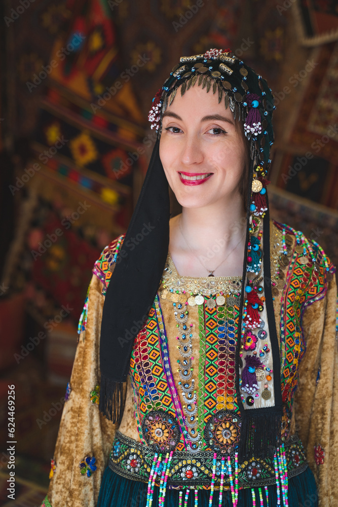 beautiful girl dressed in Turkish national clothes in the room with the interior there are many carpets on the walls