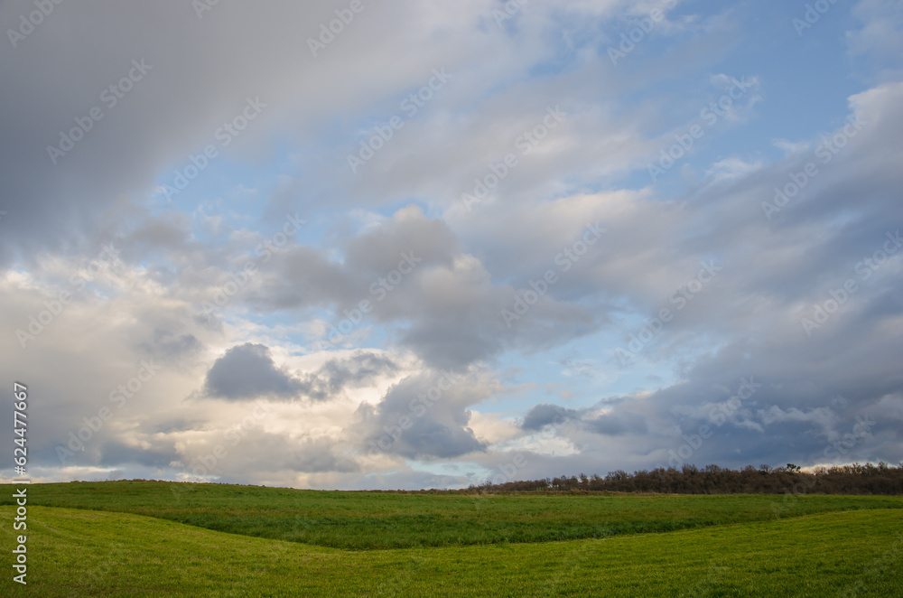 Campo Verde en pendiente con cielo azul y fondo de nubes.