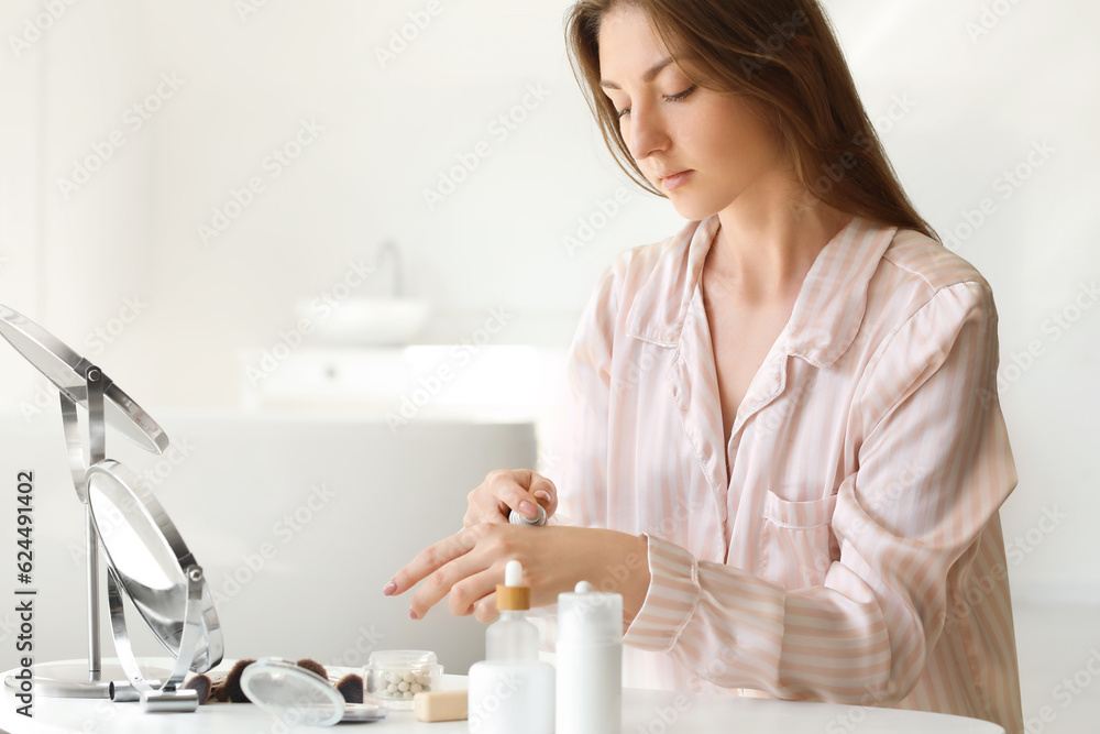 Young woman applying makeup foundation onto her hand at home Young woman applying makeup foundation onto her hand at home