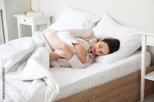 Young woman having menstrual cramps in bedroom