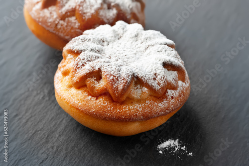 Fresh muffin. Muffin is sprinkled with powdered sugar. Close-up of muffins on a dark textured background