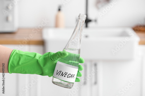 Tableau sur toile Female hand in rubber glove with bottle of vinegar in kitchen
