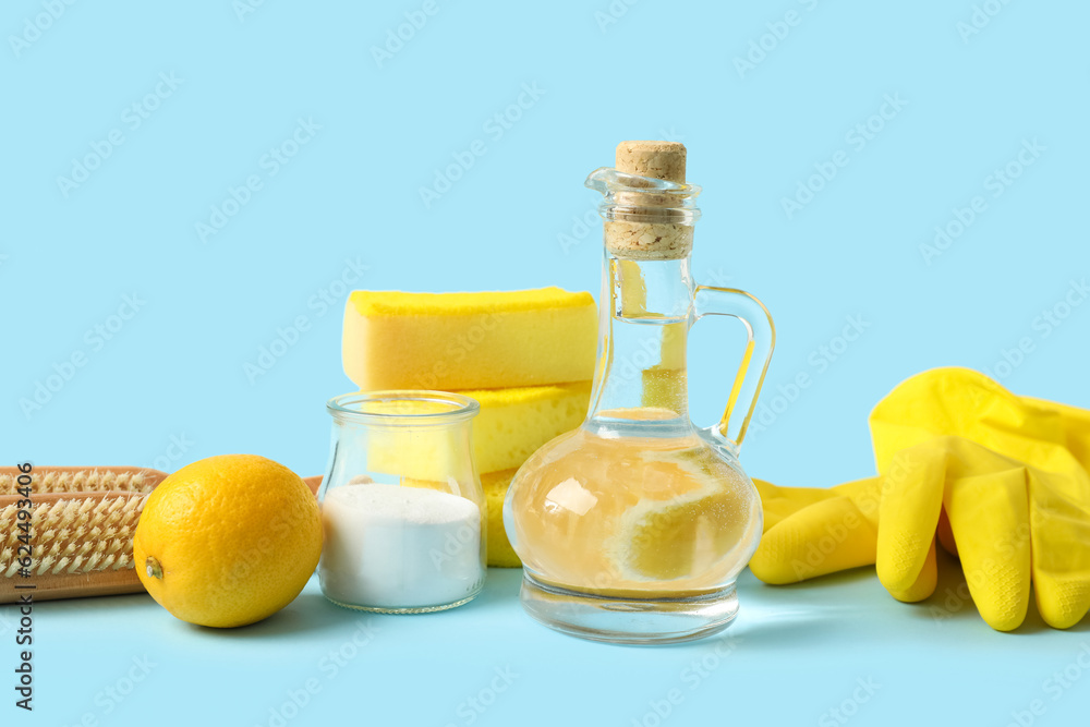 Jug of vinegar, baking soda, sponges, brushes, rubber gloves and lemon on color background Jug of vinegar, baking soda, sponges, brushes, rubber gloves and lemon on color background