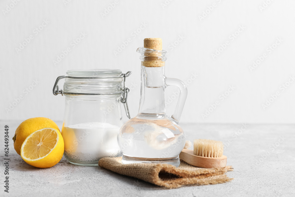 Jug of vinegar, baking soda, brush, napkin and lemons on table Jug of vinegar, baking soda, brush, napkin and lemons on table