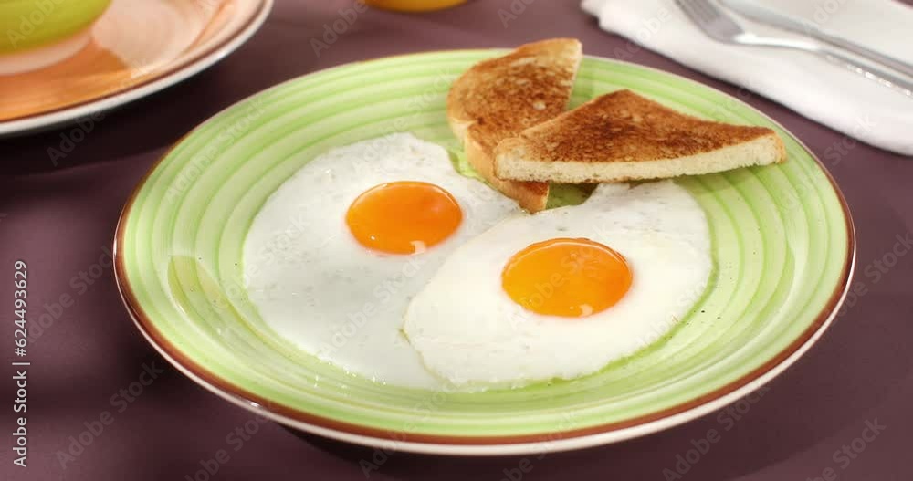 fried eggs with toast on a green plate. close-up. angle view. camera tracking. colored background. traditional breakfast. sunny day. fried eggs with toast on a green plate. close-up. angle view. camera tracking. colored background. traditional breakfast. sunny day.