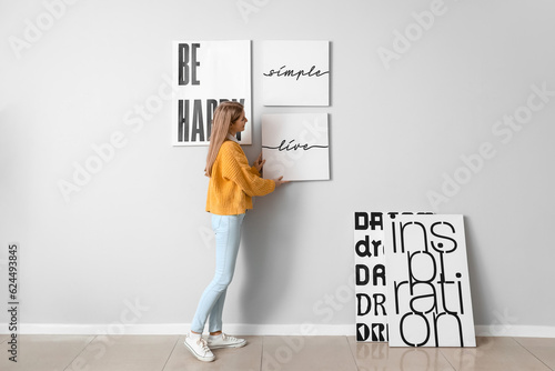 Young woman hanging poster ...