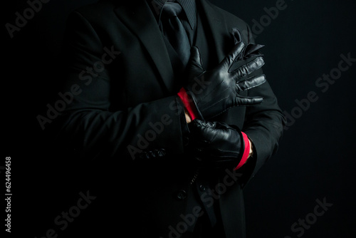 Portrait of Mysterious Man in Dark Suit Pulling on Leather Gloves Menacingly. Mafia Hit Man or Violent Gangster.
