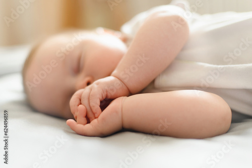 Cute baby sleeps peacefully in his crib at home, lying on his side.The concept of independent sleep,childhood protection