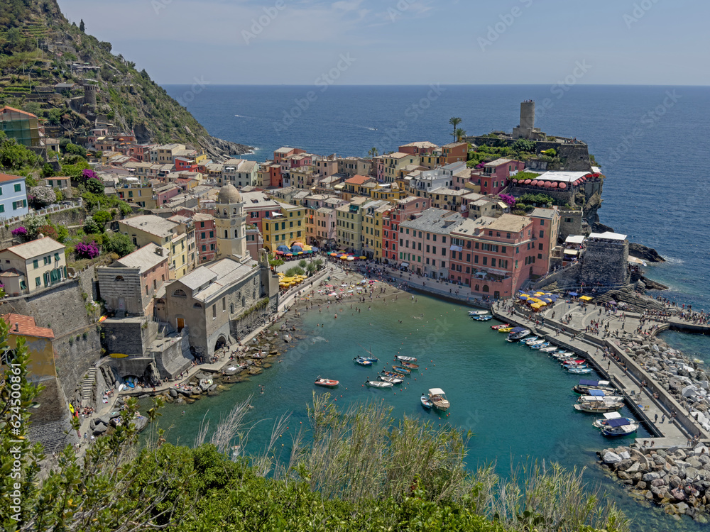 The colorful village of Vernazza, with its marina in the foreground, is shown with the Gulf of Genoa in the background during the day. This is one of the villages in Italys famed Cinque Terre region.