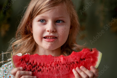 little girl with long blond hair eats a watermelon