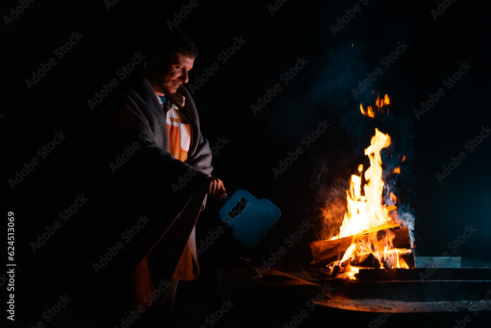 Man preparing bbq grill to cook on fire. Outside dark shot. Freeze moment of fire Man preparing bbq grill to cook on fire. Outside dark shot. Freeze moment of fire